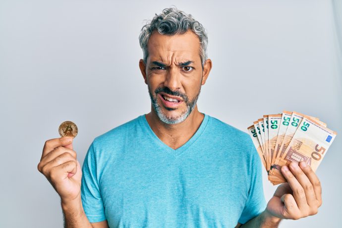 Mit Krypto Geld verdienen – Chancen und Realität 2025 Mann hält eine Bitcoin-Münze in der einen und Euro-Banknoten in der anderen Hand – symbolisch für das Geldverdienen mit Krypto