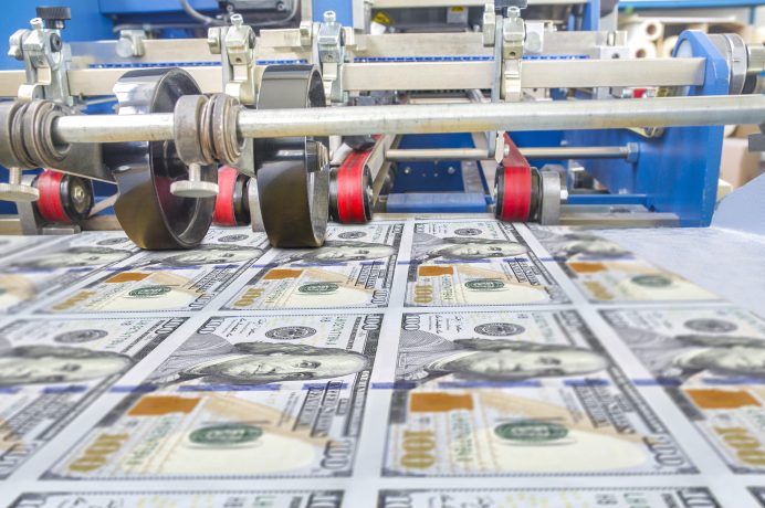 Neu gedruckte 100-Dollar-Scheine durchlaufen eine industrielle Druckmaschine in einer Währungsproduktionsanlage, die den Kontrast zwischen traditionellem Geld und aufstrebenden digitalen Vermögenswerten wie Krypto hervorhebt.