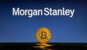 Ein Stapel physischer Bitcoin-Token wird vor einem verschwommenen Morgan-Stanley-Logo gezeigt, was die wachsende Schnittmenge zwischen Krypto-Investitionen und traditionellen Finanzdienstleistungen verdeutlicht.