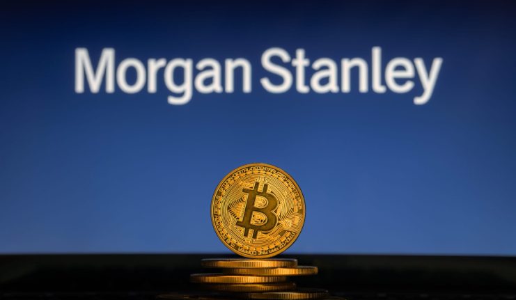 Ein Stapel physischer Bitcoin-Token wird vor einem verschwommenen Morgan-Stanley-Logo gezeigt, was die wachsende Schnittmenge zwischen Krypto-Investitionen und traditionellen Finanzdienstleistungen verdeutlicht.