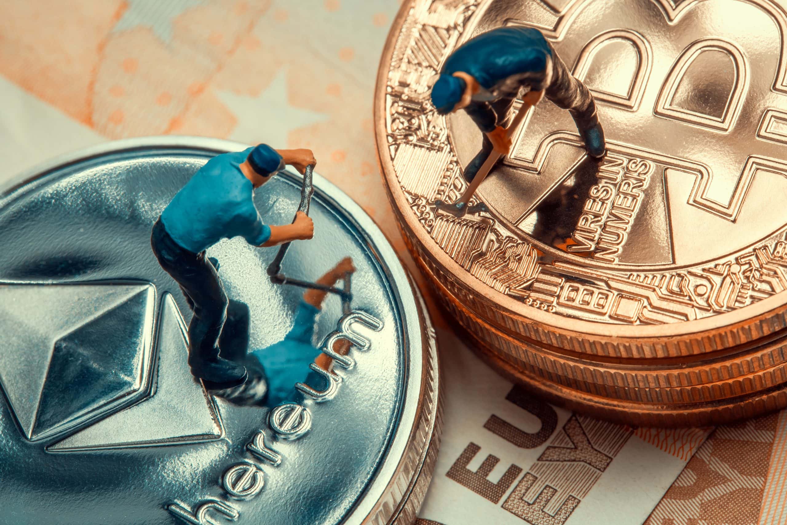 Zwei Miniaturfiguren scheinen auf großen physischen Darstellungen von Ethereum- und Bitcoin-Münzen zu schürfen, die Millionäre in Vorbereitung und die sich entwickelnden Krypto-Strategien 2025 symbolisieren, alles vor einem Hintergrund aus Papierwährung.