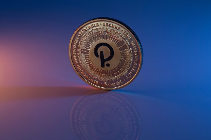 Eine goldfarbene Polkadot (DOT) Kryptowährungsmünze, die als Ethereum-Killer bezeichnet wird, steht aufrecht auf einer spiegelnden Oberfläche mit blauem und orangefarbenem Hintergrund.