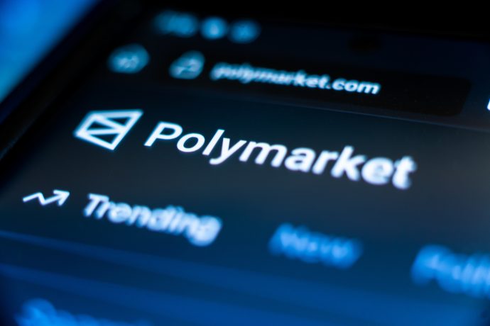 Nahaufnahme eines Smartphone-Bildschirms, auf dem die Polymarket-Website angezeigt wird. Im Mittelpunkt stehen das Logo, das Wort "Trending" unter der Navigationsleiste und Hinweise auf einen bevorstehenden Token-Airdrop.