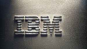 Nahaufnahme des IBM-Logos in Metallbuchstaben mit Streifendesign, montiert auf einer strukturierten dunklen Oberfläche, die die Innovation von IBM im Bereich Digitale Assets und Plattformlösungen widerspiegelt.