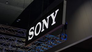 Sony hat eine Krypto-Bankenlizenz beantragt Ein großes schwarz-weißes Sony-Schild hängt von der Decke über einer Metalltraversenkonstruktion in einem überdachten Sony-Veranstaltungsraum.
