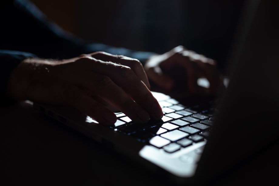 Nahaufnahme von Händen, die bei schwachem Licht auf einer Laptop-Tastatur tippen, während die Telegram-App auf dem Bildschirm geöffnet ist.