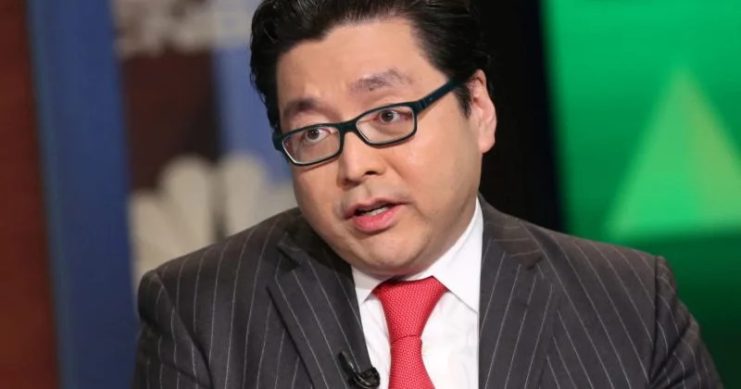 Tom Lee, gekleidet in einen dunklen Nadelstreifenanzug, eine rote Krawatte und eine Brille, spricht während eines Fernsehinterviews in einer Studioumgebung über Ethereum und Kapitalflut.