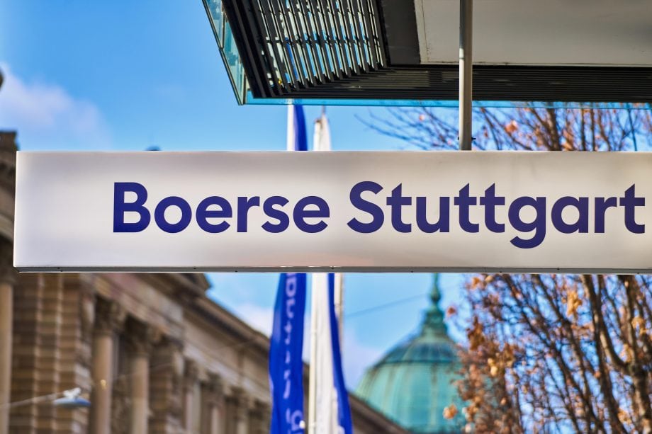 Ein Schild der Börse Stuttgart ist im Freien zu sehen, mit einem modernen Gebäude und einer Kuppel im Hintergrund.