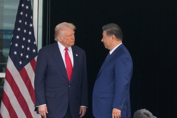 South Korea China Trump Asia Zwei Männer in Anzügen, von denen einer vor einer US-Flagge steht, stehen sich gegenüber und scheinen ein ernstes Gespräch zu führen.
