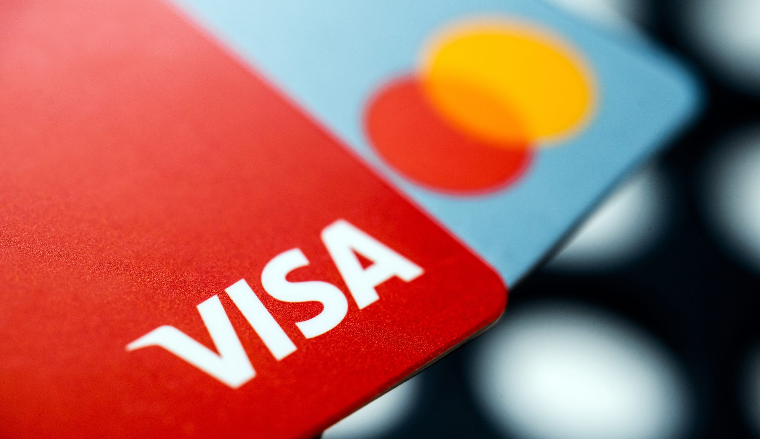 Visa erweitert Stablecoin-Angebot auf vier neue Blockchains Nahaufnahme einer roten Visa-Kreditkarte, die eine blaue Mastercard-Kreditkarte überlagert, wobei die Logos von Visa und Mastercard deutlich sichtbar sind.