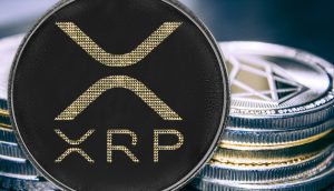 Eine Nahaufnahme einer physischen XRP-Münze, die prominent vor einem Stapel anderer metallischer Kryptowährungsmünzen angezeigt wird.