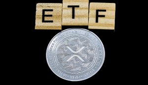 Eine glänzende XRP-Münze ist unter drei Holzkacheln platziert, die ETF auf einem schwarzen Hintergrund buchstabieren.