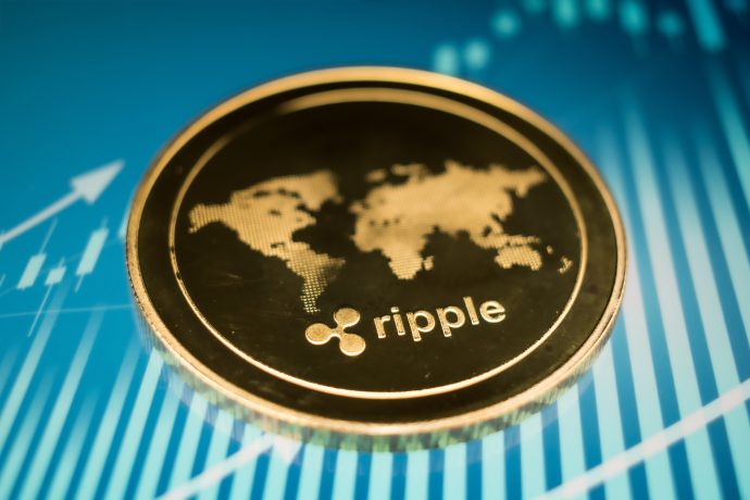 Eine goldene XRP-Münze mit einer Weltkarte auf blauem Hintergrund und Finanzdiagrammen.