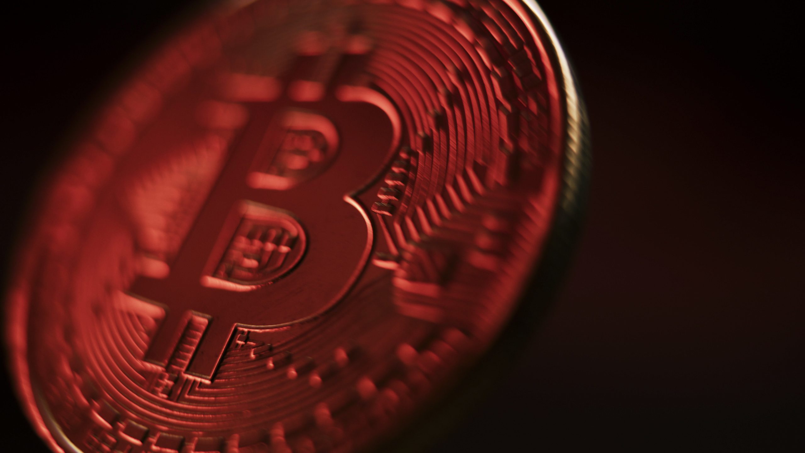 Nahaufnahme einer physischen Bitcoin-Münze mit detaillierten kreislaufähnlichen Mustern und dem markanten Bitcoin-Symbol in der Mitte, das das Wesen von Bitcoin mit einem unverwechselbaren rötlichen Farbton einfängt.