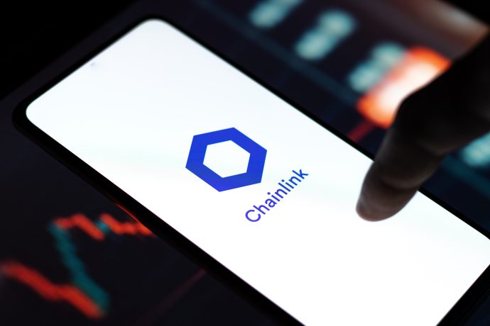 Ein Smartphone zeigt das Chainlink-Logo und den Namen auf dem Bildschirm, während ein unscharfer Finger darauf zeigt und eine Grafik im Hintergrund die wachsende Präsenz von Chainlink im digitalen Finanzwesen unterstreicht.