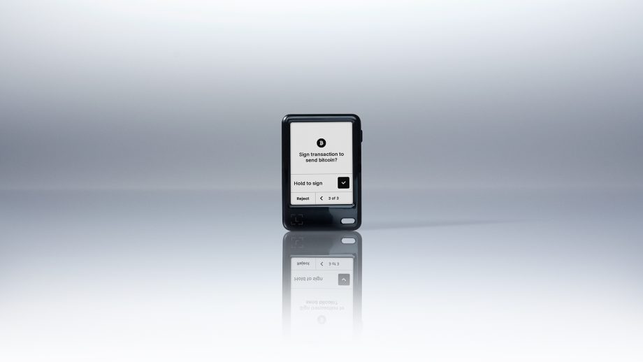 Der Ledger Nano Gen5 mit einem Bildschirm zeigt eine Aufforderung zur Unterzeichnung einer Transaktion an, mit Aktionstasten und einem minimalen, reflektierenden Hintergrund.