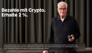 Ein älterer Mann mit Brille steht in einem Haus und hält ein kleines Gerät. Der Text neben ihm lautet: Bezahle mit Crypto über Trade Republic. Erhalte 2 %. Vorhang im Hintergrund, zusätzlicher Disclaimer-Text darunter.