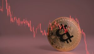 Eine Bitcoin-Münze taumelt, dazu ein abstürzender Chart in rot