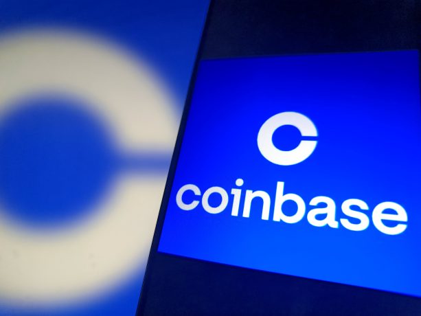 Ein digitaler Bildschirm zeigt das Coinbase-Logo und den Namen in weißer Schrift auf blauem Hintergrund, mit einem verschwommenen Coinbase-Logo im Hintergrund.