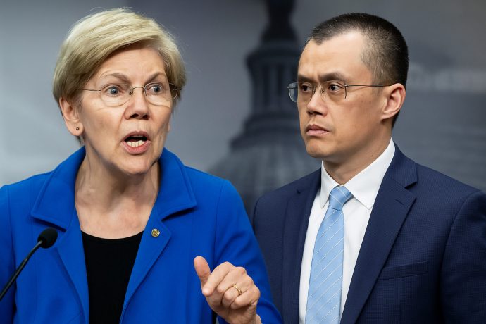 Eine Frau in einem blauen Blazer spricht an einem Podium, während CZ, in einem Anzug und mit Brille, neben ihr steht, beide vor einem unscharfen Hintergrund.
