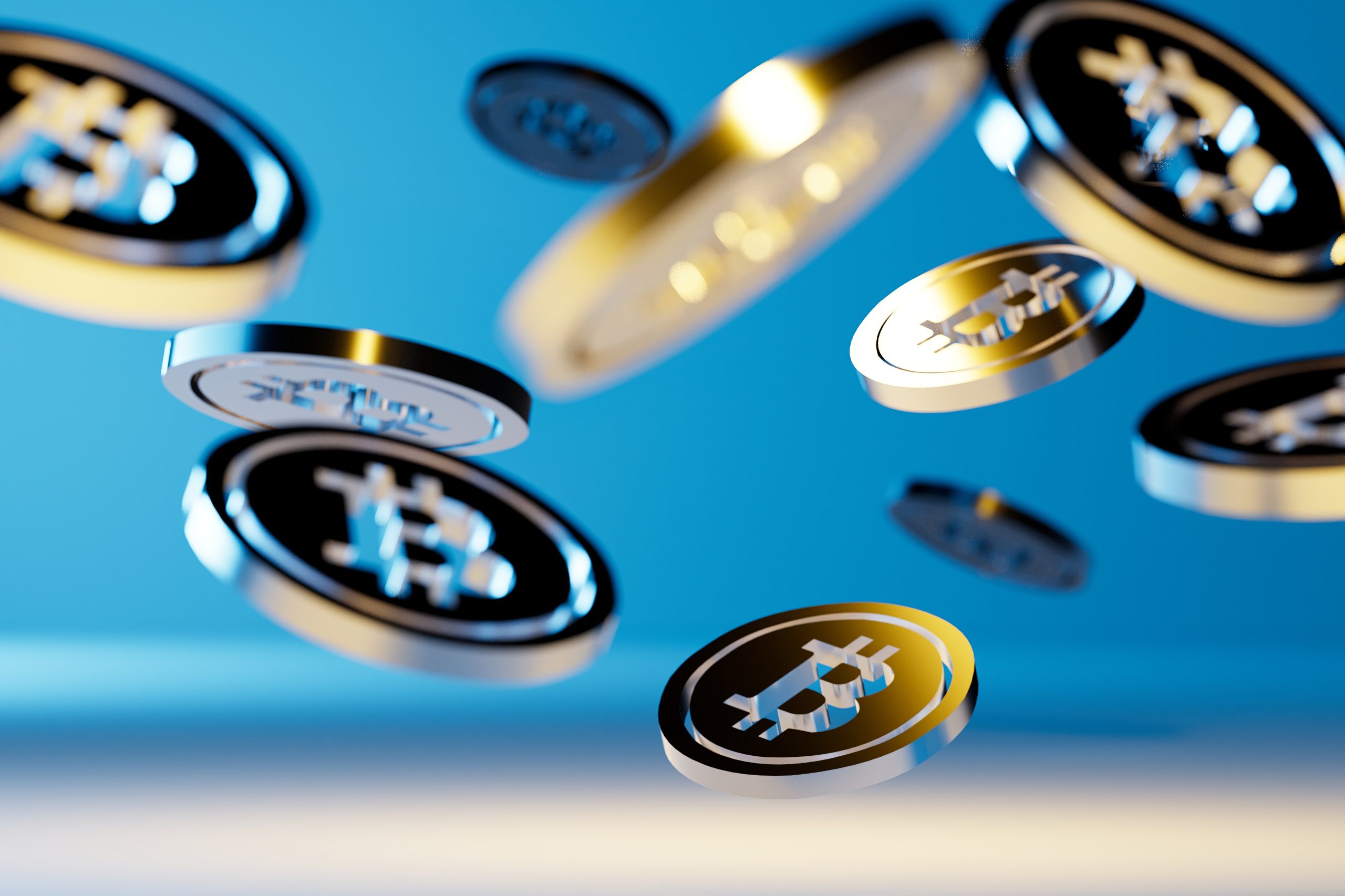 Mehrere metallische Bitcoin-Münzen sind vor einem blauen Hintergrund zu sehen.