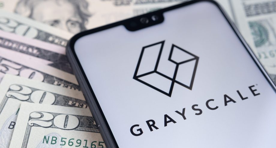 Ein Smartphone zeigt das Grayscale-Logo auf seinem Bildschirm an, das auf verstreuten US-Dollarnoten liegt.