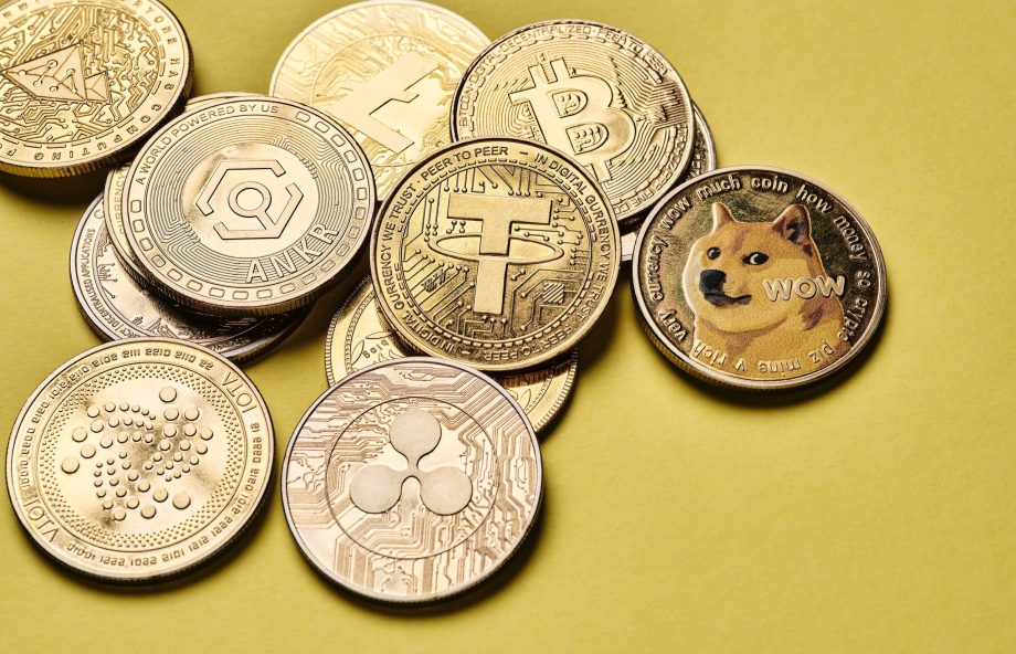 Eine Sammlung verschiedener Krypto-Münzen, darunter Bitcoin, Tether, Dogecoin und andere, angeordnet auf einem gelben Hintergrund.