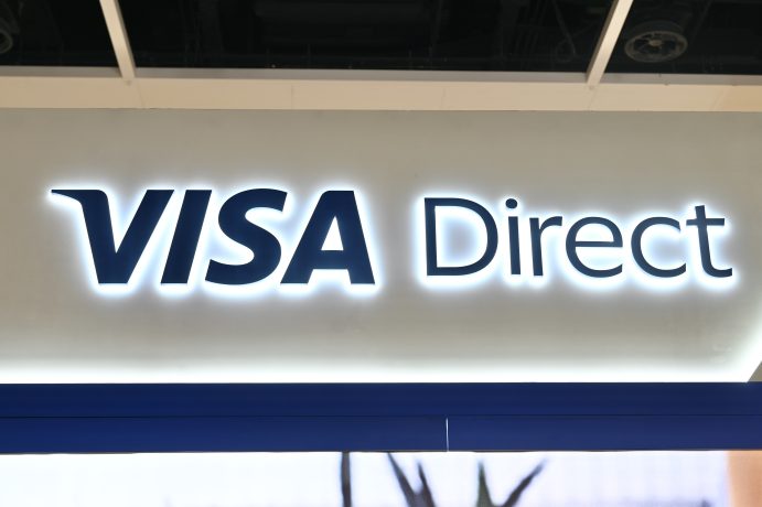 Ein beleuchtetes Schild mit dem Schriftzug Visa Direct in fetten blauen Buchstaben auf weißem Hintergrund hebt die vertrauenswürdige Marke Visa hervor.