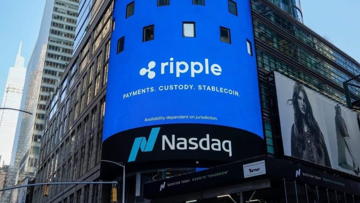 Der Canary Spot XRP ETF ist gestern an der Nasdaq gestartet. Eine große blaue Ripple-Werbung mit dem Nasdaq-Logo und dem Hinweis auf XRP wird auf einer digitalen Werbetafel in einer von hohen Gebäuden umgebenen Stadt gezeigt.
