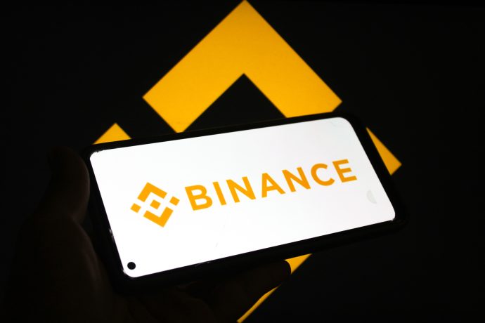 Das Bild zeigt ein Smartphone, auf dem das Binance-Logo zu sehen ist
