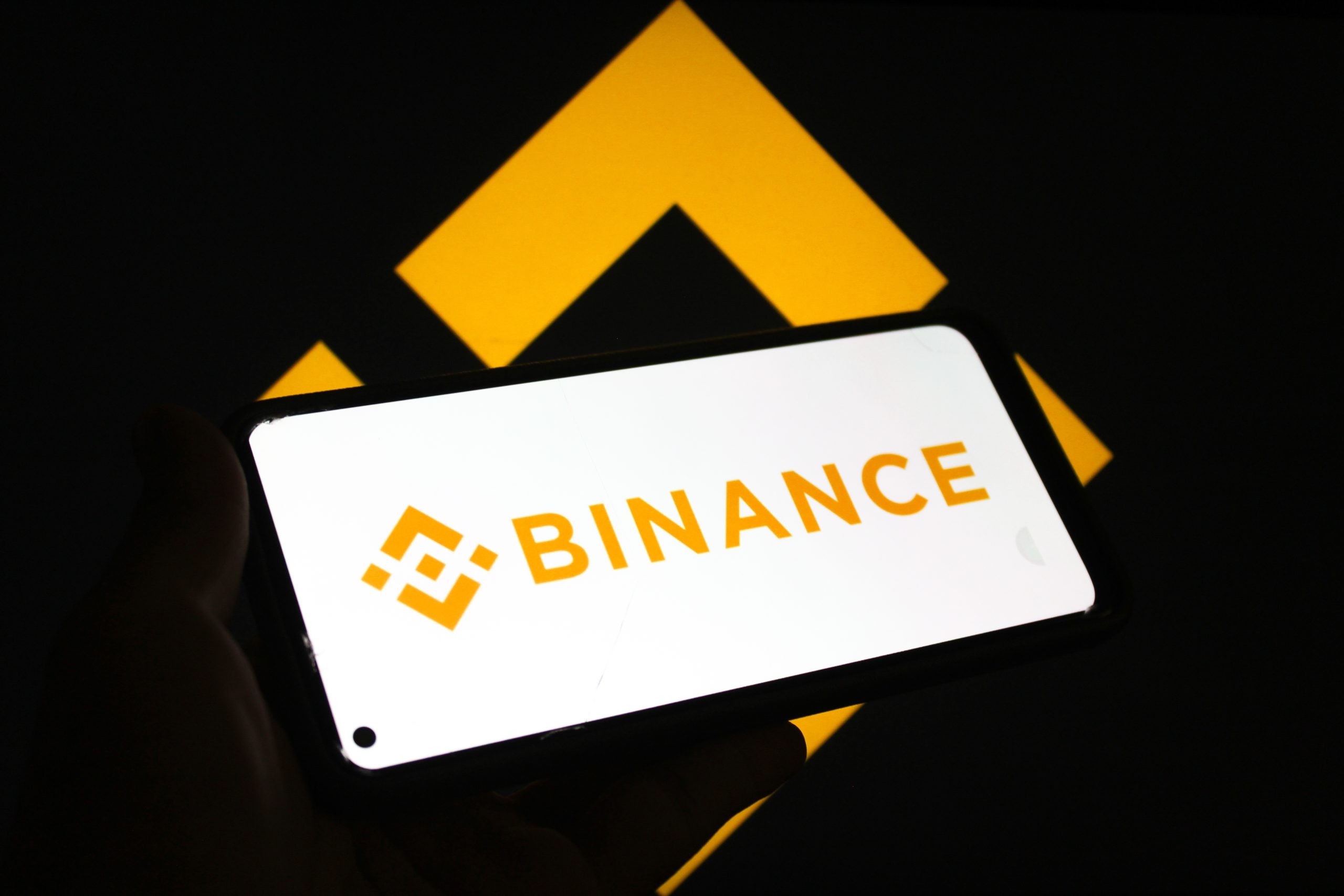 Das Bild zeigt ein Smartphone, auf dem das Binance-Logo zu sehen ist