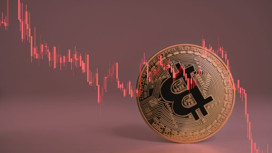 Bitcoin-Münze vor Chart mit negativer Kursentwicklung