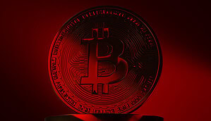 Eine Bitcoin-Münze vor rotem Hintergrund
