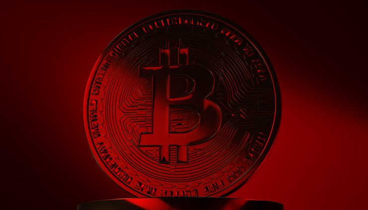 Eine Bitcoin-Münze vor rotem Hintergrund