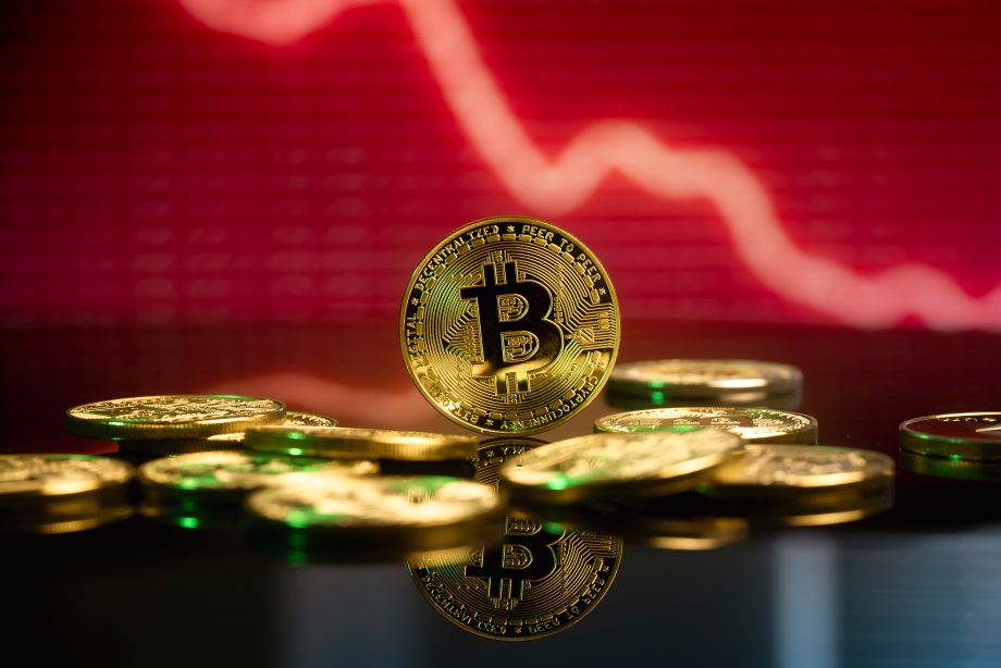 Bitcoin vor rotem Hintergrund, der fallende Kurse symbolisiert