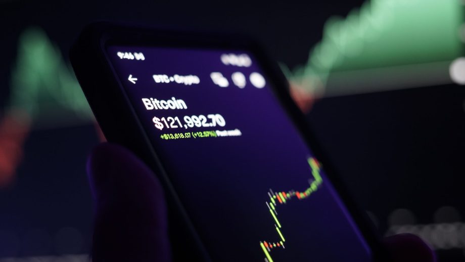 Zu sehen ist ein Smartphone mit einem Bitcoin-Kursverlauf