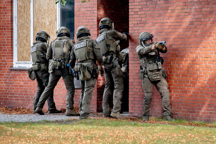Symbolbild zeigt, wie schwerbewaffnete Einsatzkräfte der Polizei ein Gebäude stürmen.