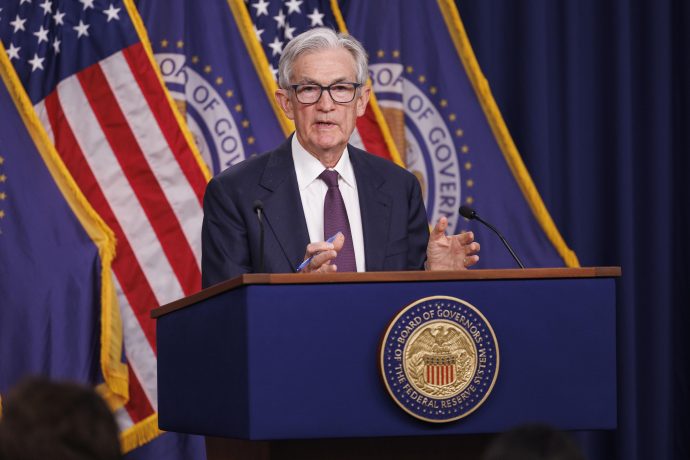 Ein Mann im Anzug steht vor einem Rednerpult der Federal Reserve. Im Hintergrund sind US-Flaggen.