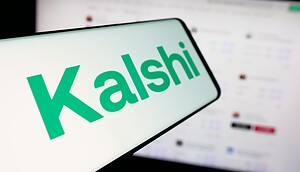 Kalshi-Logo auf einem Smartphone vor einem Computerbildschirm.