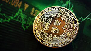 Eine goldfarbene Bitcoin-Münze ruht auf einem Bildschirm mit grünen Finanzgraphen und Zahlen, die den Kryptowährungshandel und die Marktaktivitäten im November symbolisieren.