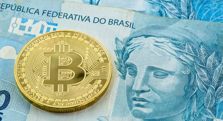 Eine Bitcoin-Münze liegt auf einem brasilianischen Geldschein