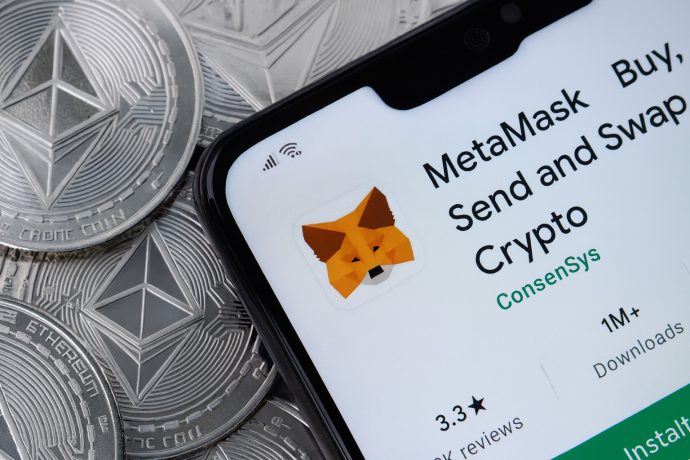MetaMask-Wallet auf Display von Smartphone, das auf Ethereum-Münzen liegt