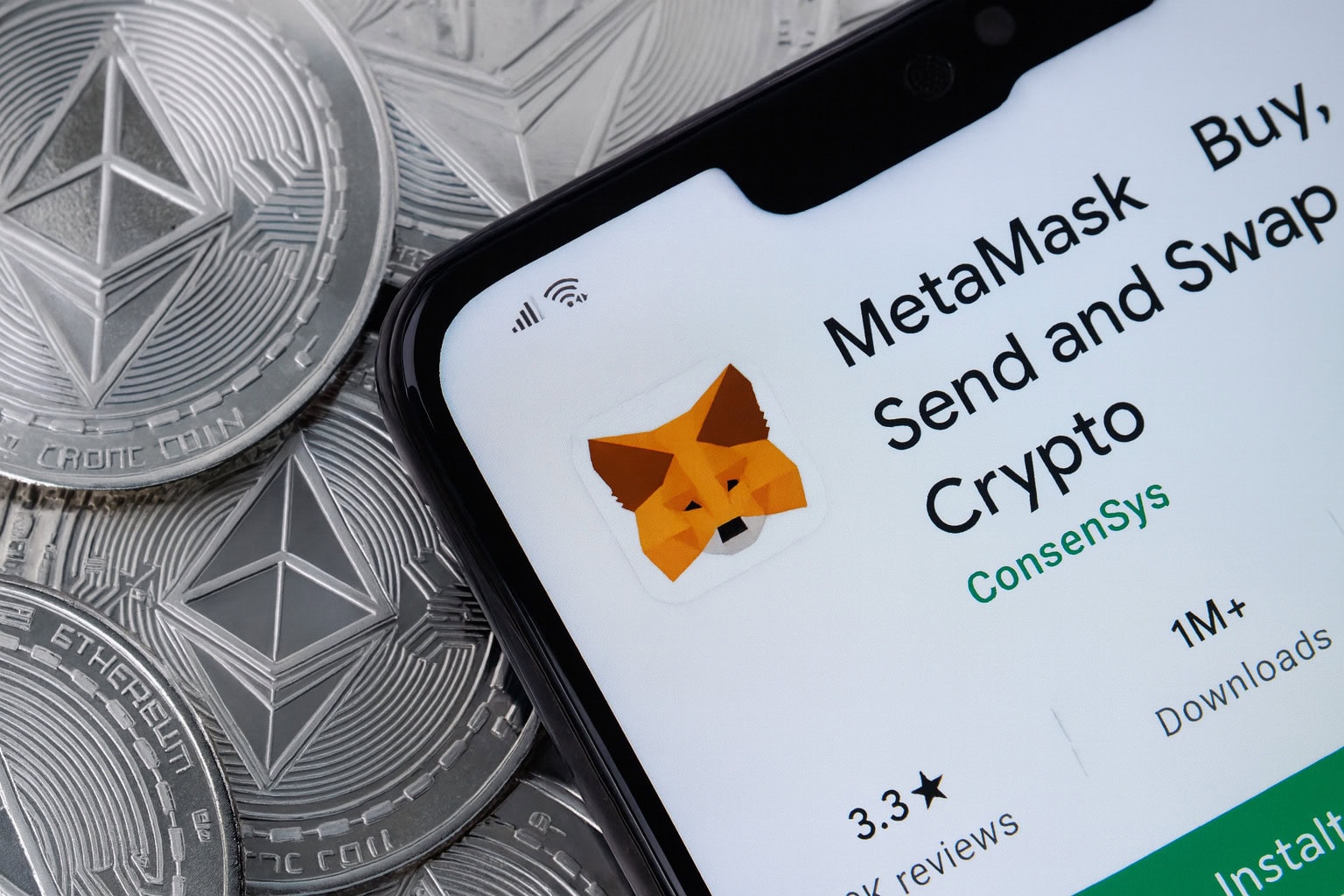 MetaMask-Wallet auf Display von Smartphone, das auf Ethereum-Münzen liegt