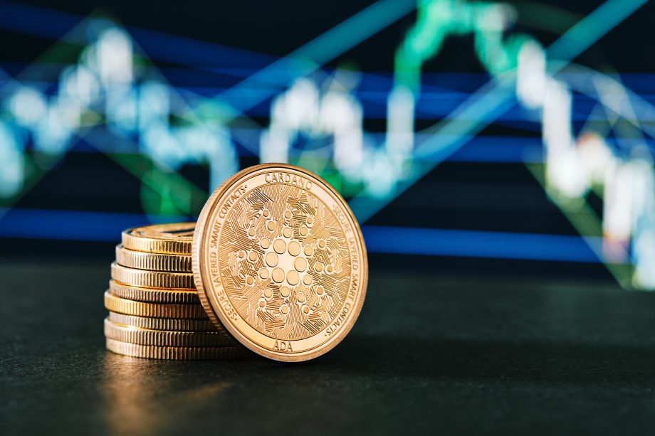 Ein Stapel Cardano-Münzen vor einem Kurs-Chart.