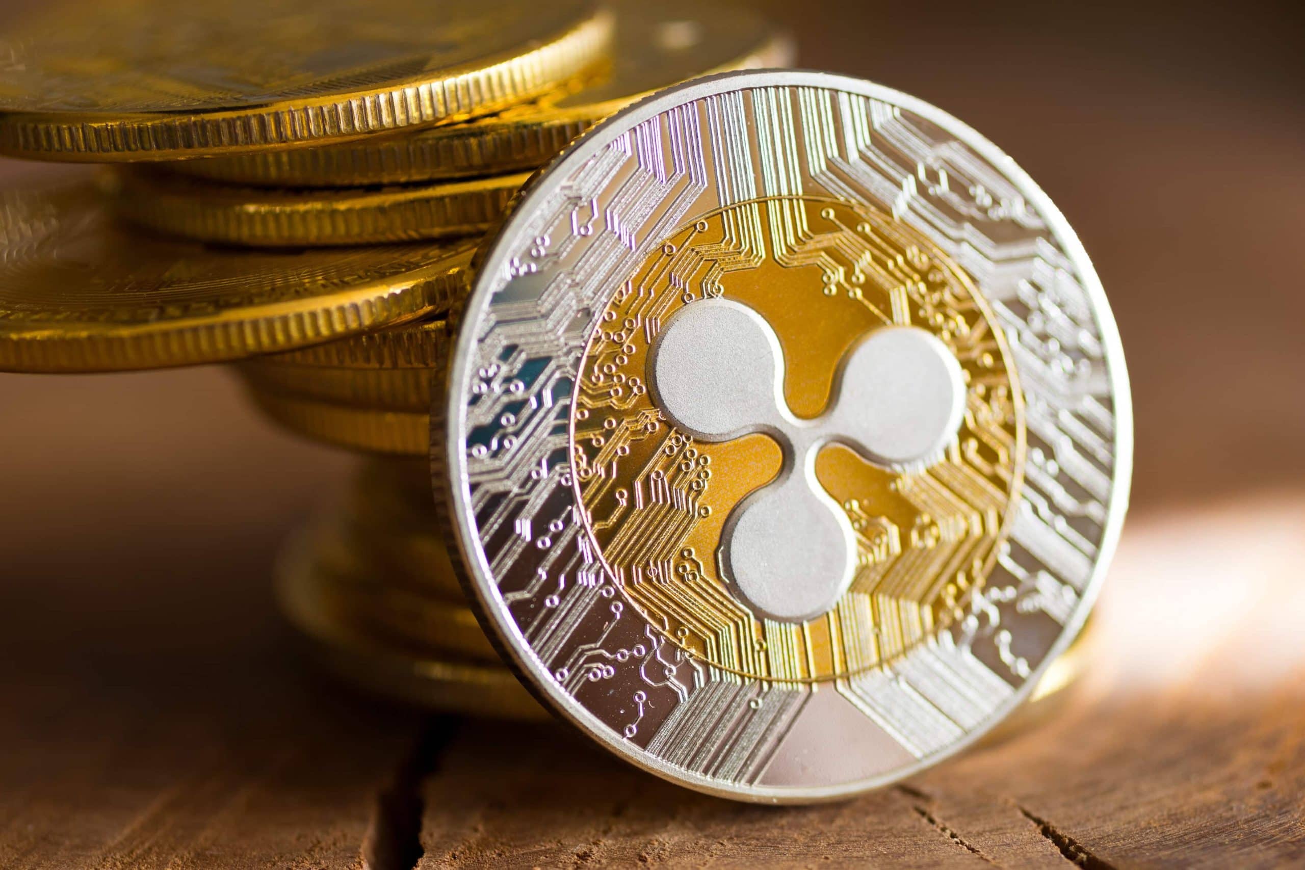 Eine Nahaufnahme einer XRP-Kryptowährungsmünze mit ihrem Logo, vor einem Stapel von XRP-Münzen