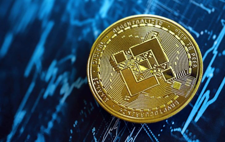Kommt jetzt der bullishe Kursausbruch? Eine goldene BNB Binance-Münze ruht auf einem blauen Hintergrund, auf dem Finanzcharts und Datengrafiken zu sehen sind.