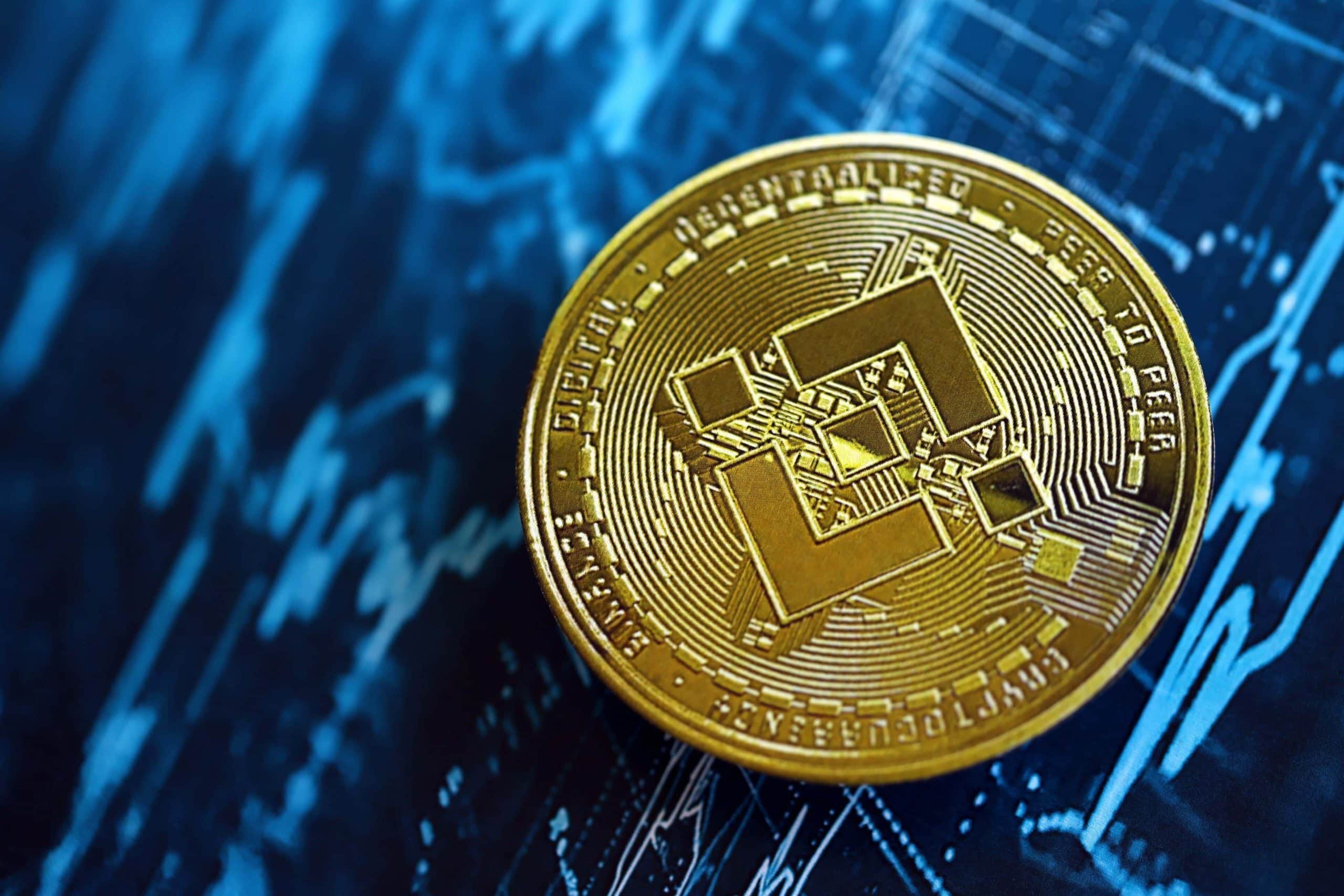 Eine goldene BNB Binance-Münze ruht auf einem blauen Hintergrund, auf dem Finanzcharts und Datengrafiken zu sehen sind.