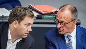 Zwei Männer in Anzügen sitzen eng beieinander und führen ein ernstes Gespräch in einer scheinbar formellen Sitzung oder Konferenz, in der möglicherweise ein automatisch gespeicherter Krypto-Entwurf besprochen wird.