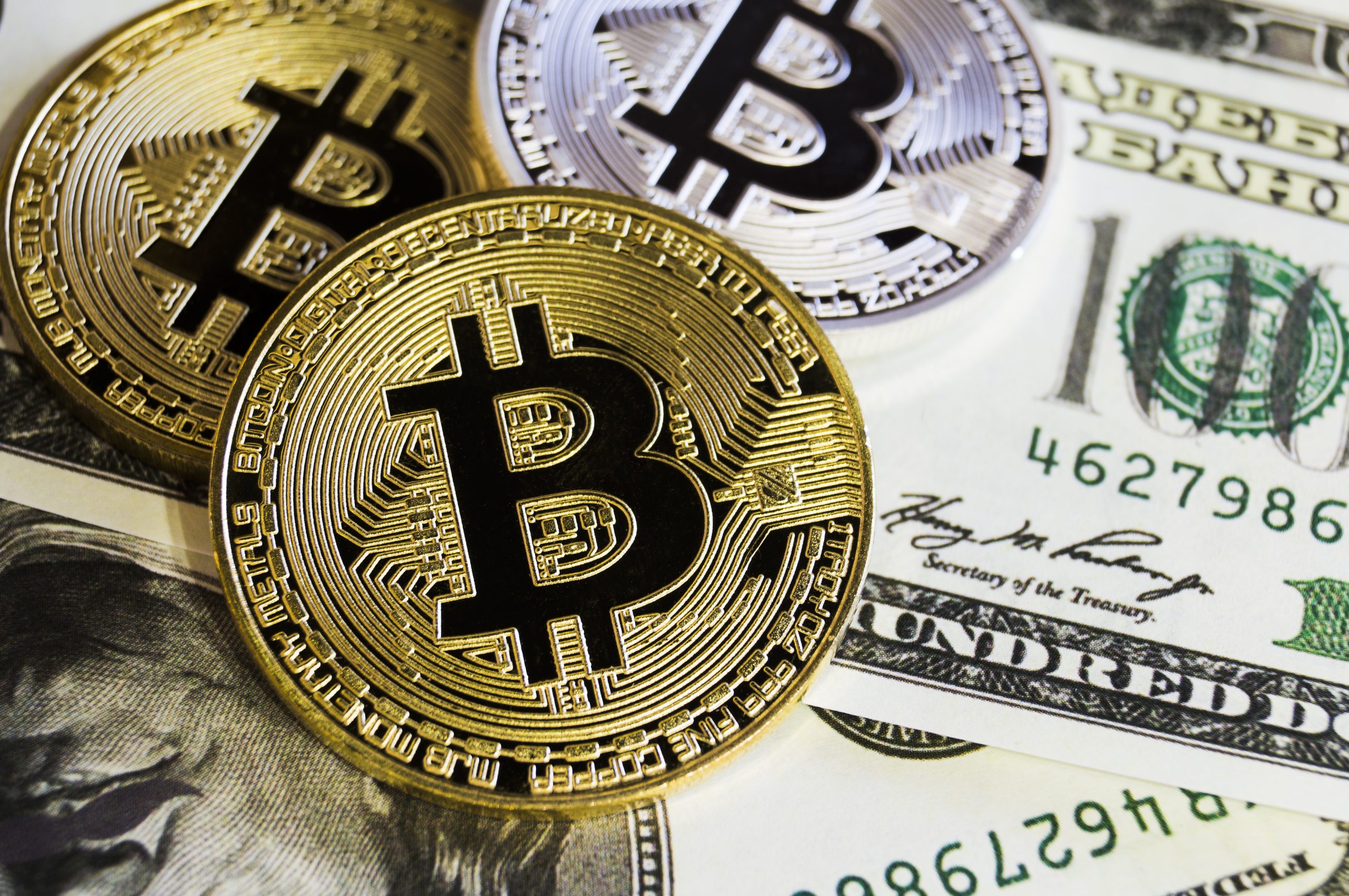 Bitcoin-Münzen liegen auf US-Dollarscheine