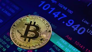 Bitcoin-Münze auf einem Display mit einer Kursanzeige von 100.000 US-Dollar